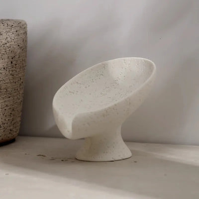 Speckled beige stone soap holder on a neutral background